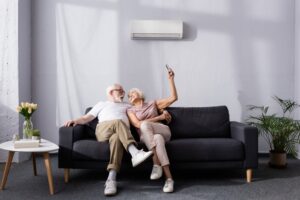 couple-sitting-on-couch-in-front-of-a-ductless-air-handler